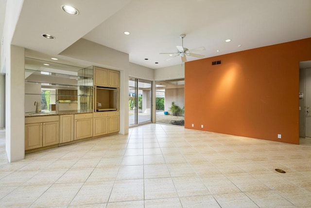 unfurnished living room featuring ceiling fan, a healthy amount of sunlight, light tile patterned floors, and sink