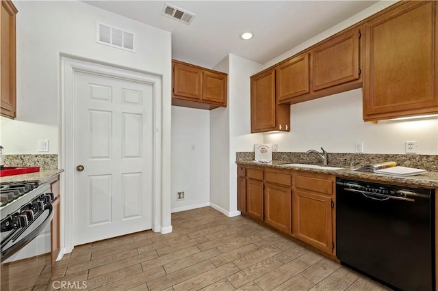 kitchen featuring dishwasher, light hardwood / wood-style floors, light stone counters, and sink