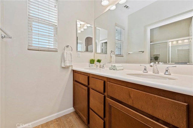 bathroom with hardwood / wood-style floors, vanity, and a shower with shower door