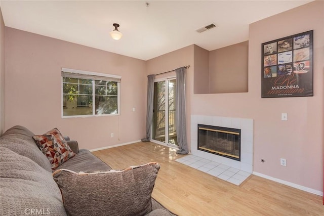 living room featuring a tiled fireplace and hardwood / wood-style flooring