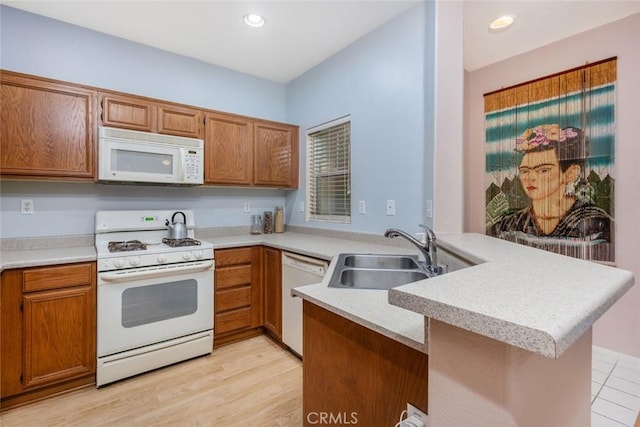 kitchen with sink, light hardwood / wood-style floors, kitchen peninsula, and white appliances