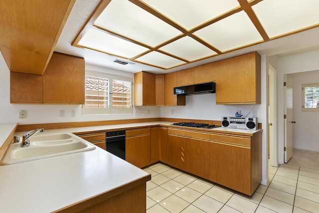 kitchen with kitchen peninsula, gas stovetop, sink, exhaust hood, and light tile patterned floors