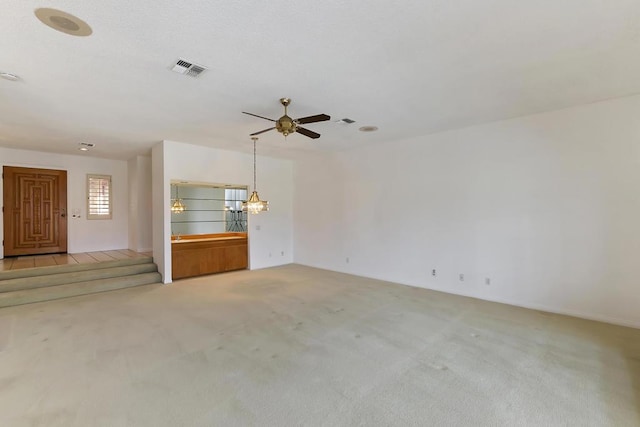 unfurnished living room with ceiling fan with notable chandelier and light colored carpet