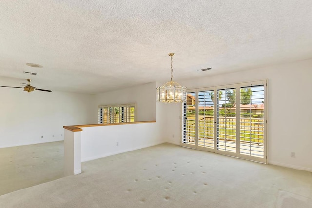 carpeted empty room with ceiling fan with notable chandelier and a textured ceiling