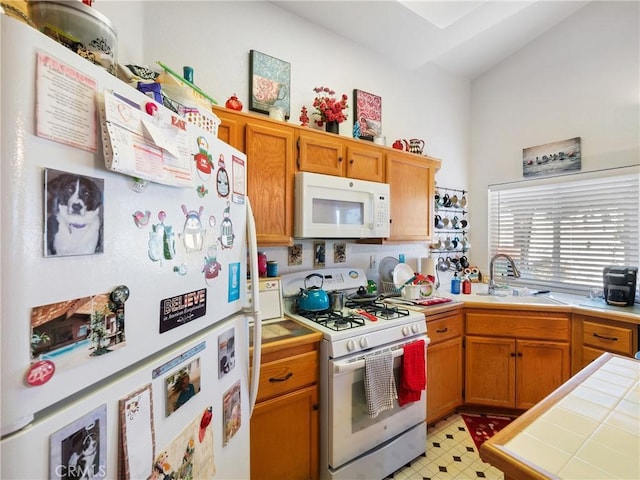 kitchen featuring white appliances, tile countertops, lofted ceiling, and sink