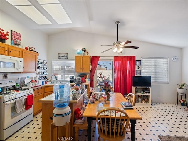 kitchen with vaulted ceiling with skylight, ceiling fan, gas stove, and sink