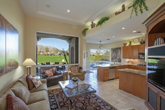 living room featuring a mountain view, plenty of natural light, ceiling fan, and sink