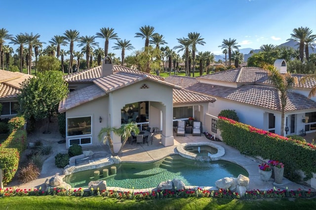 rear view of property featuring a patio area and a pool with hot tub