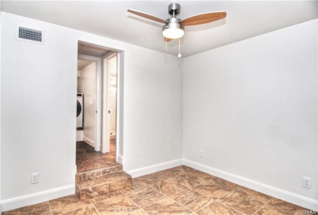 empty room featuring ceiling fan and washer / dryer