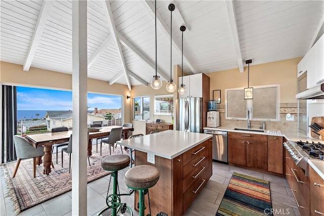 kitchen with pendant lighting, backsplash, sink, appliances with stainless steel finishes, and a kitchen island