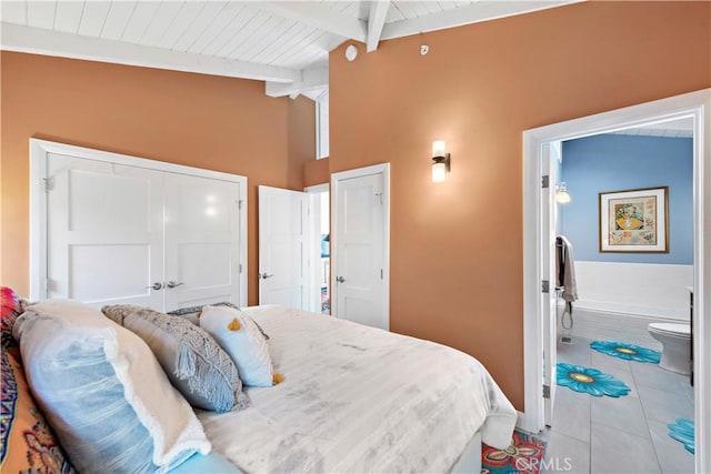 tiled bedroom with lofted ceiling with beams, wood ceiling, and connected bathroom