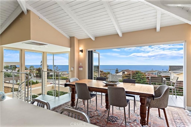 dining space featuring lofted ceiling with beams and a water view