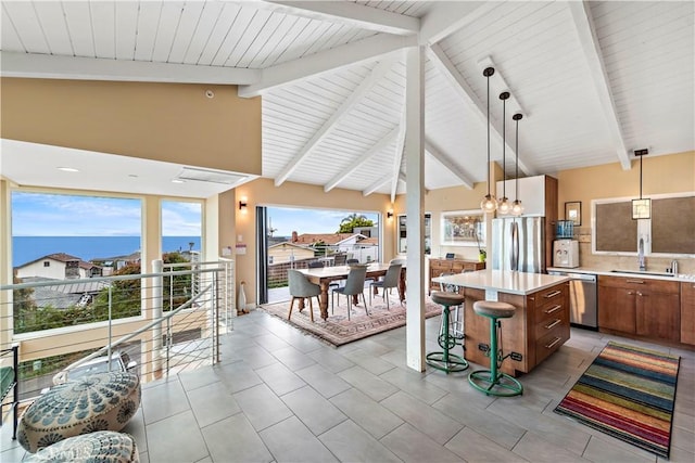 kitchen with a center island, sink, stainless steel appliances, pendant lighting, and a water view