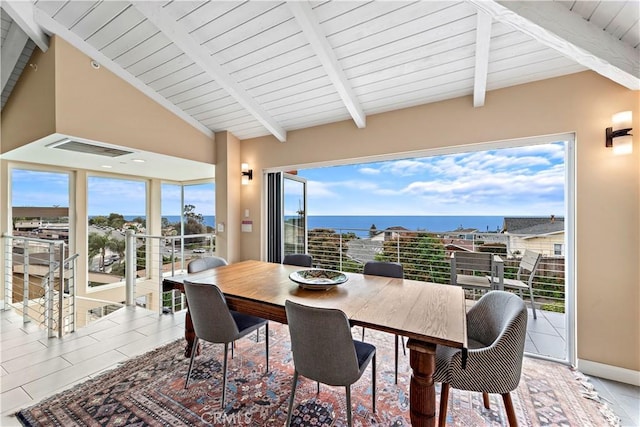 dining room with light tile patterned floors, vaulted ceiling with beams, and a water view