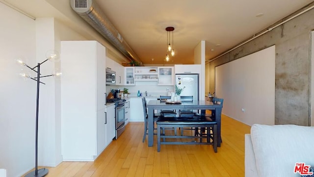 kitchen featuring appliances with stainless steel finishes, a notable chandelier, decorative light fixtures, white cabinets, and light hardwood / wood-style flooring