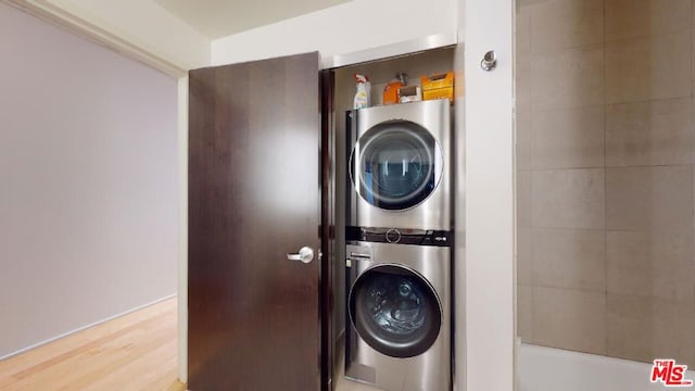 laundry room featuring stacked washer and clothes dryer and hardwood / wood-style floors