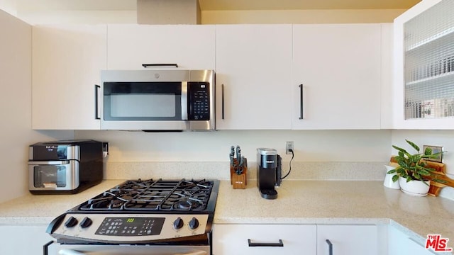 kitchen featuring white cabinets, light stone counters, and stainless steel appliances