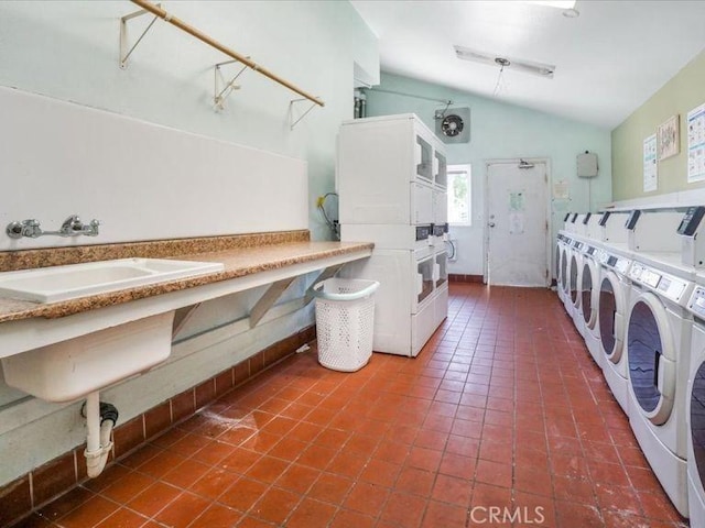 laundry area featuring stacked washer / drying machine, sink, washer and dryer, and dark tile patterned flooring