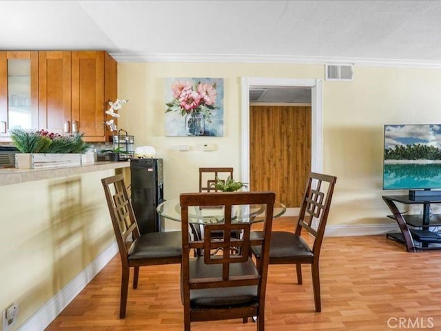 dining area featuring crown molding and light hardwood / wood-style floors