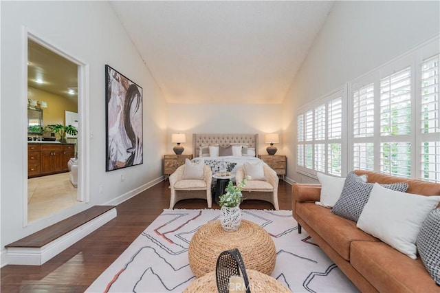 bedroom with hardwood / wood-style floors, vaulted ceiling, and ensuite bath