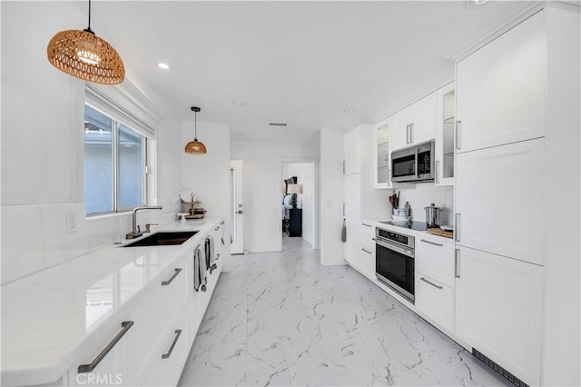 kitchen featuring stainless steel appliances, white cabinetry, hanging light fixtures, and sink