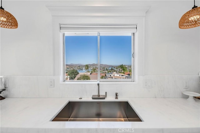 kitchen featuring light stone countertops, sink, and pendant lighting