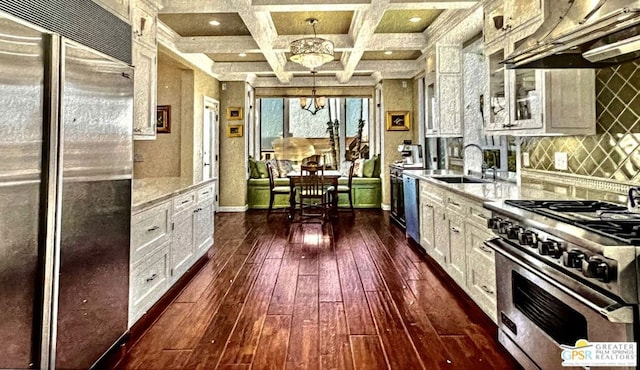 kitchen featuring coffered ceiling, premium appliances, decorative light fixtures, an inviting chandelier, and white cabinetry