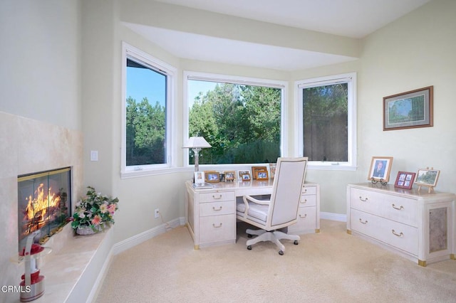 office space with a tiled fireplace and light colored carpet