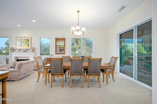 dining space featuring a healthy amount of sunlight, light colored carpet, and an inviting chandelier