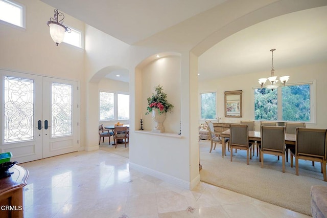 carpeted entrance foyer featuring french doors and a notable chandelier