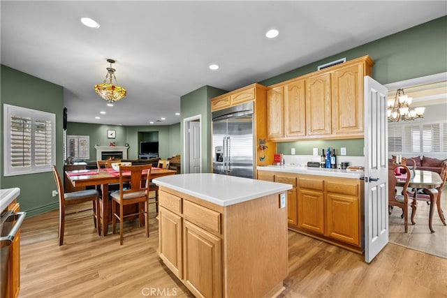 kitchen featuring a center island, an inviting chandelier, hanging light fixtures, light hardwood / wood-style flooring, and stainless steel built in refrigerator