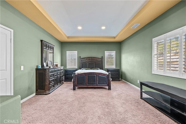 bedroom with carpet floors and a raised ceiling