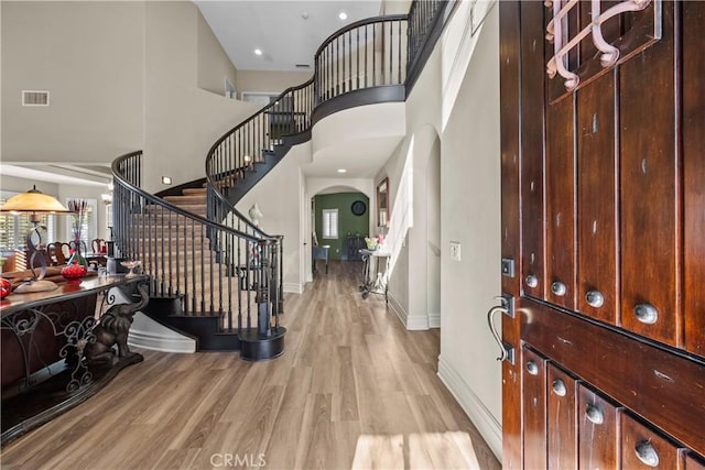 entrance foyer with light hardwood / wood-style floors and a towering ceiling