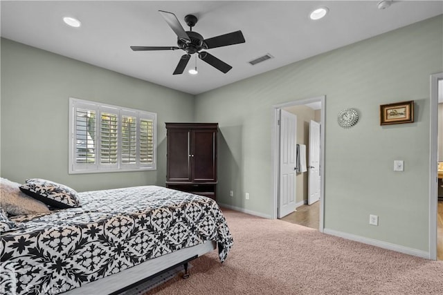 carpeted bedroom with ensuite bath and ceiling fan