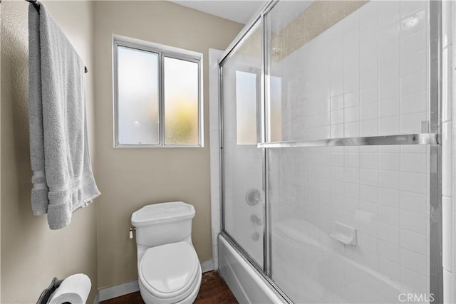 bathroom with combined bath / shower with glass door and toilet