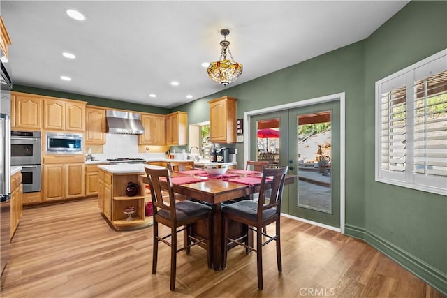 dining space with french doors, light hardwood / wood-style floors, and sink