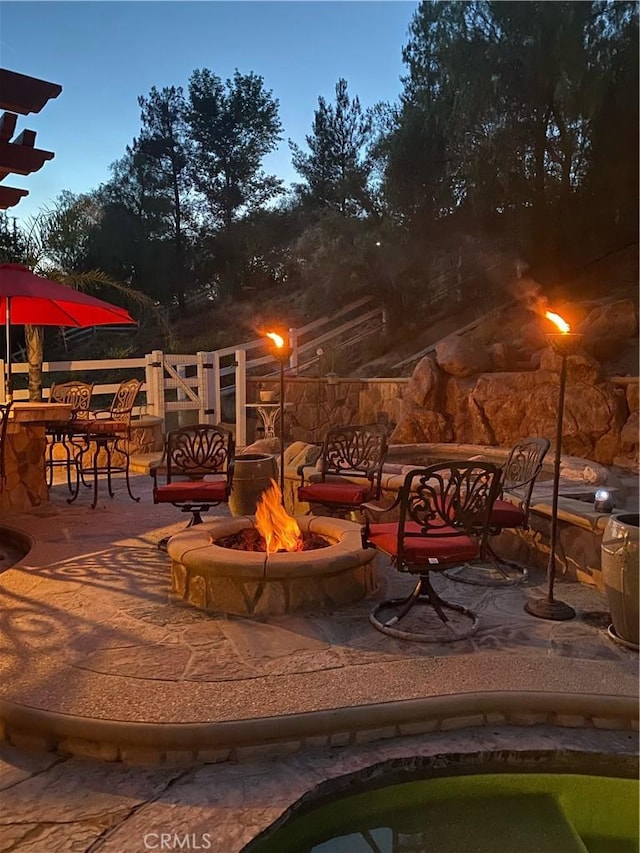 patio terrace at dusk featuring exterior bar and an outdoor fire pit