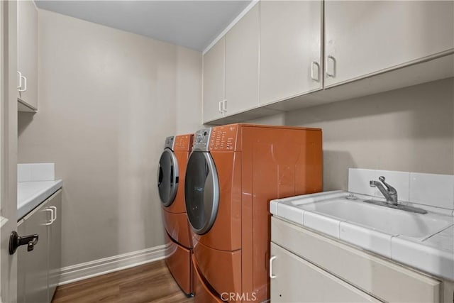 laundry room featuring cabinets, dark hardwood / wood-style flooring, sink, and washing machine and clothes dryer