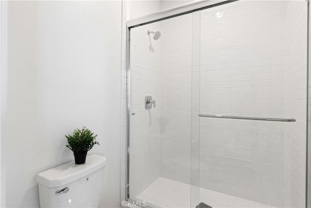 bathroom featuring toilet and a shower with door