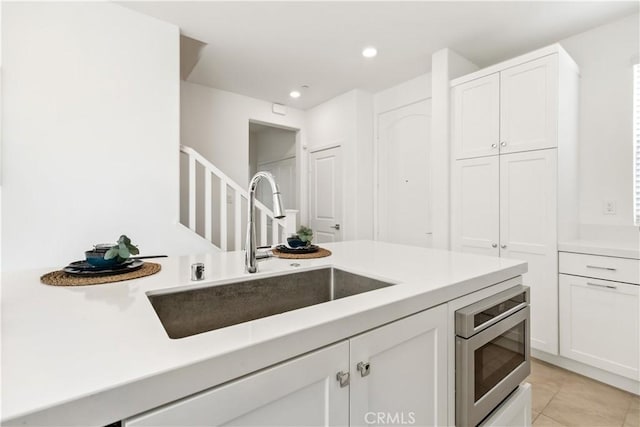 kitchen with sink, white cabinetry, and light tile patterned floors