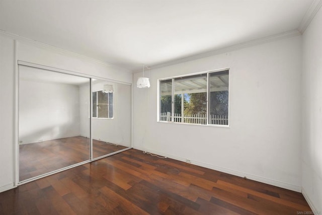 unfurnished bedroom featuring dark hardwood / wood-style floors, a closet, and crown molding