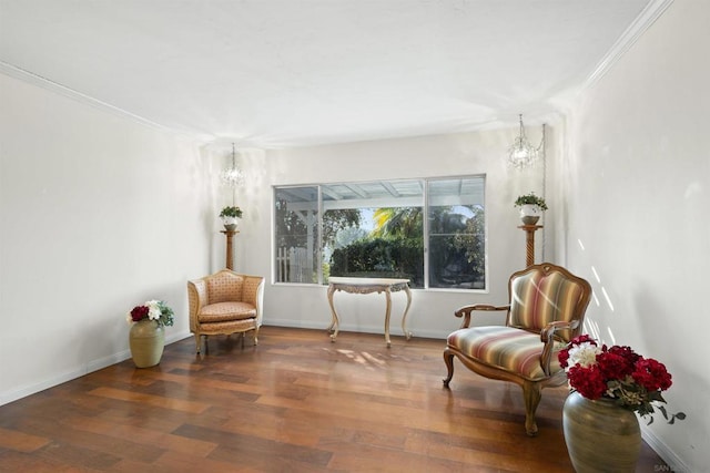 living area featuring dark hardwood / wood-style flooring, ornamental molding, and a notable chandelier