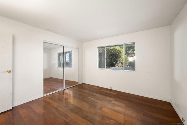 unfurnished bedroom with dark hardwood / wood-style flooring and a closet