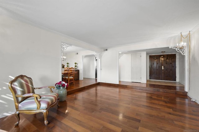 living area with dark hardwood / wood-style floors, ornamental molding, and an inviting chandelier