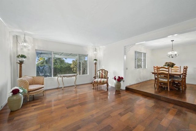 living area featuring crown molding, dark wood-type flooring, and a notable chandelier