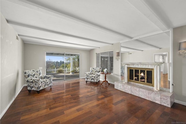 unfurnished room featuring a tile fireplace, dark hardwood / wood-style floors, and beamed ceiling