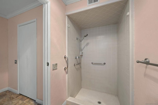 bathroom with ornamental molding and tiled shower