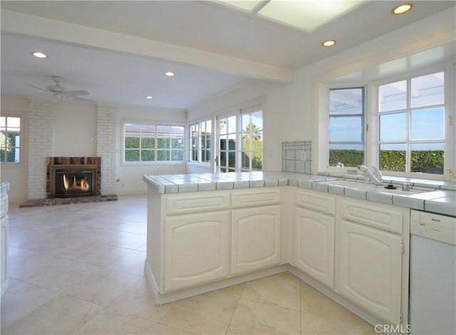 kitchen featuring a wealth of natural light, tile countertops, dishwasher, and kitchen peninsula