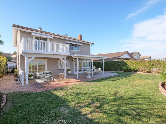 back of house featuring an outdoor living space, a patio area, a lawn, and a balcony