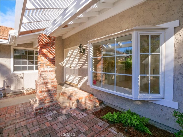 exterior space featuring a pergola, a tiled roof, brick siding, and stucco siding